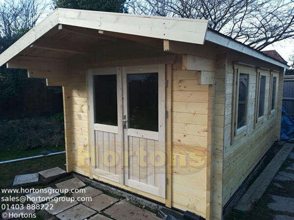 3m x 5m garden cabin front and glazed side wall in garden on slabbed base